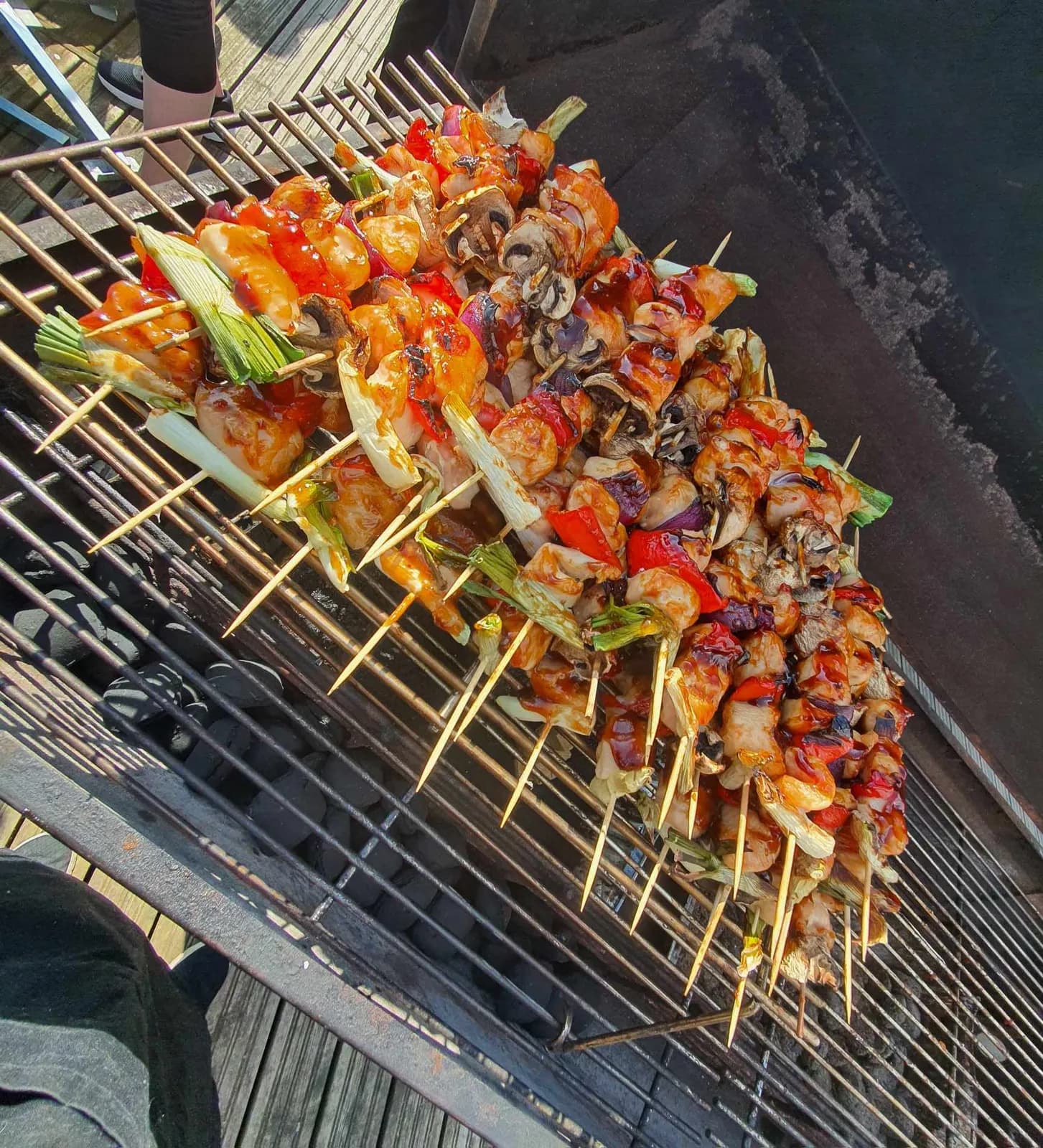 Grillspyd med kød og peberfrugt på række over kullene