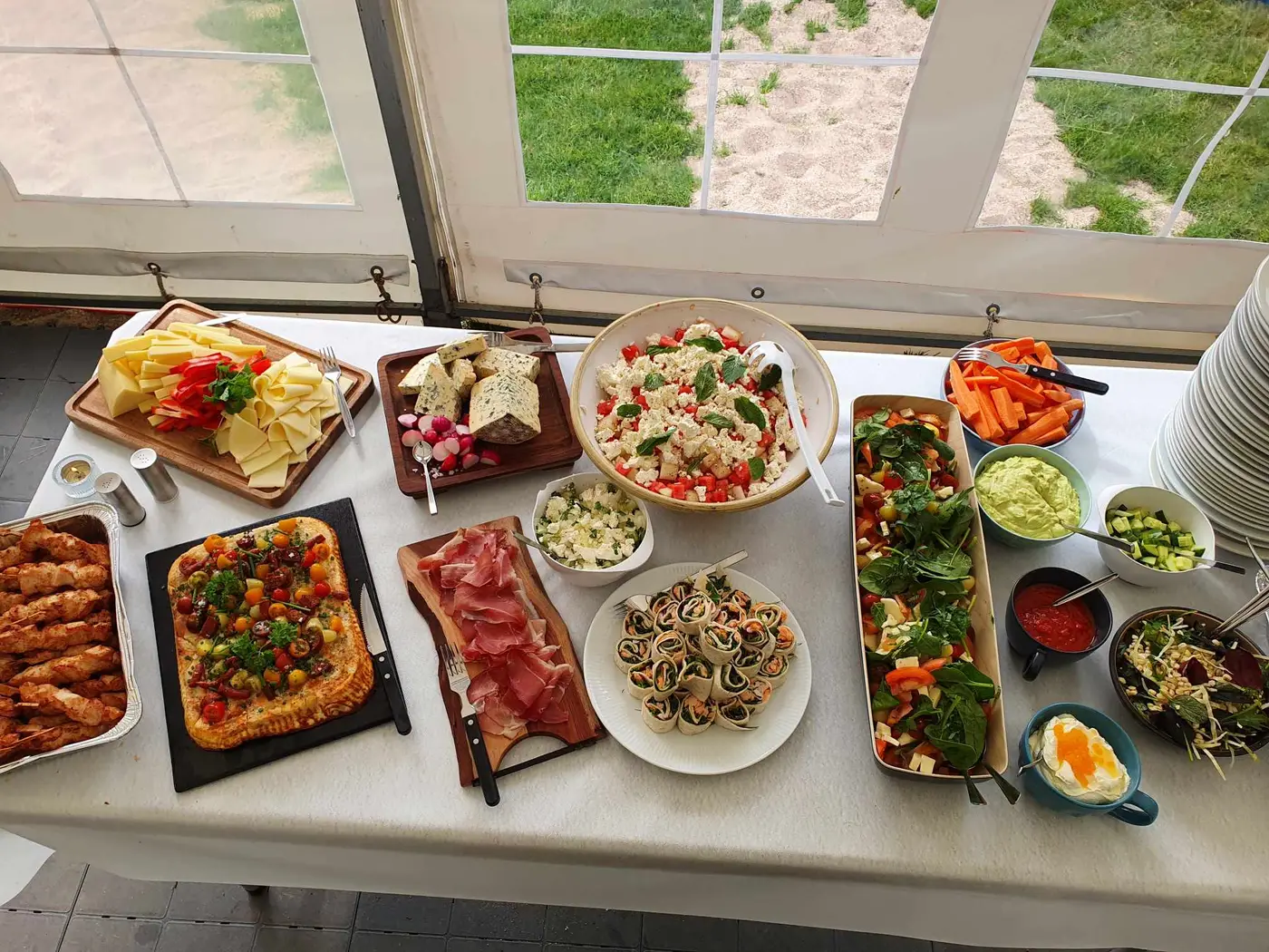 Buffet anrettet på langbord i festtelt med oste, salater, wraps og spyd